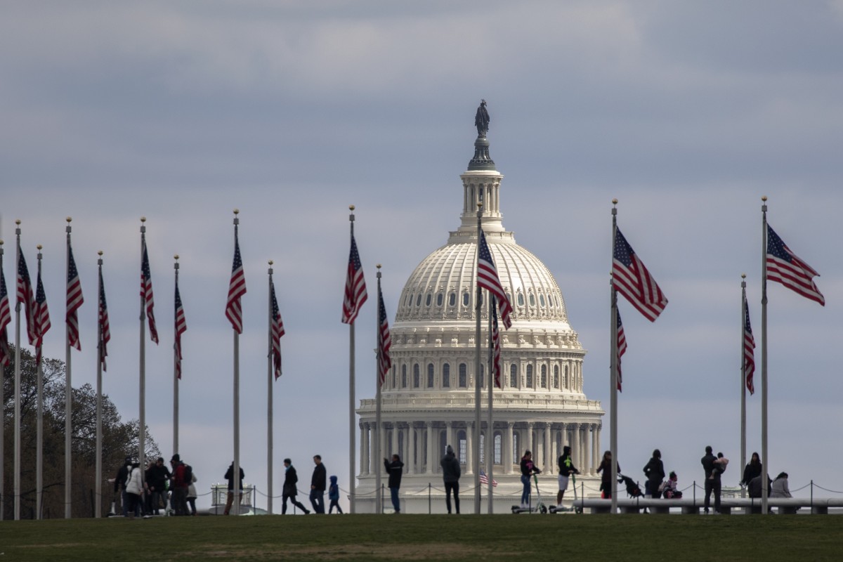 People walk among U.S. flags with the U.S. Capitol in the background, Sunday, March 15, 2020, in Washington. Photo: Jacquelyn Martin/AP Photo