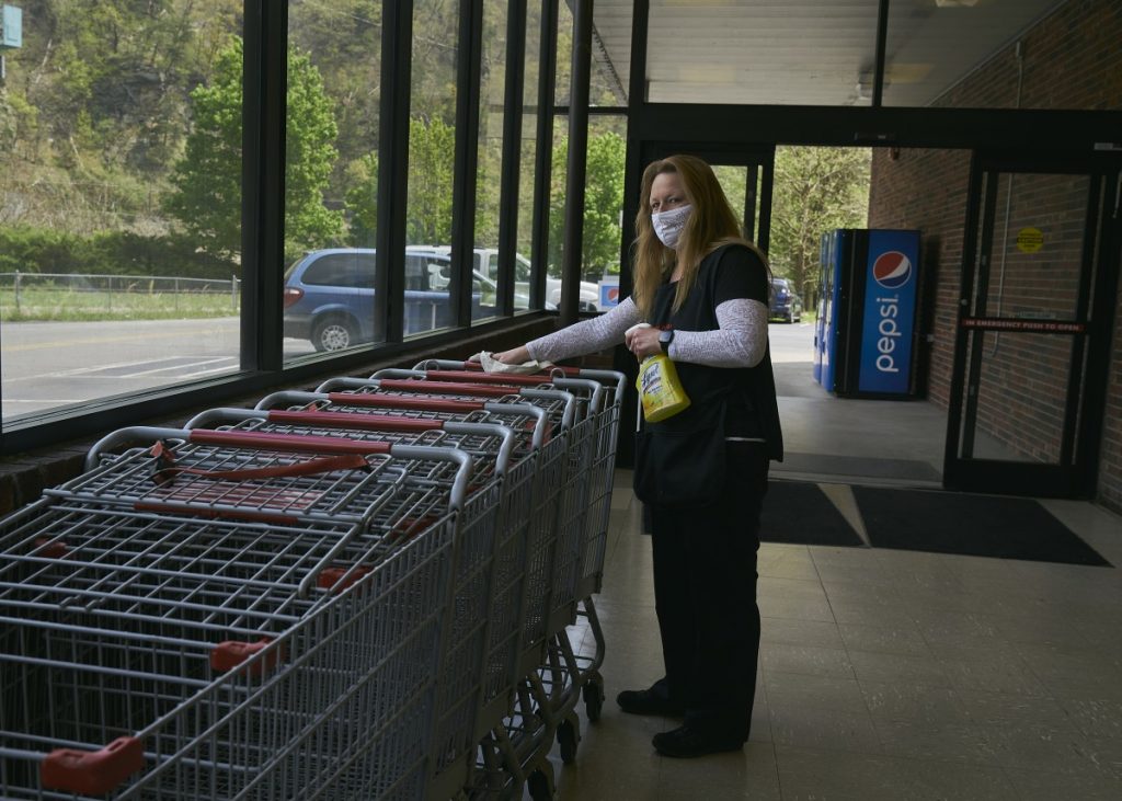 Foodland in Gilbert, West Virginia, is the only grocery store in Mingo County. Drema Curry sanatizes carts. Photo: Stacy Kranitz/100 Days in Appalachia