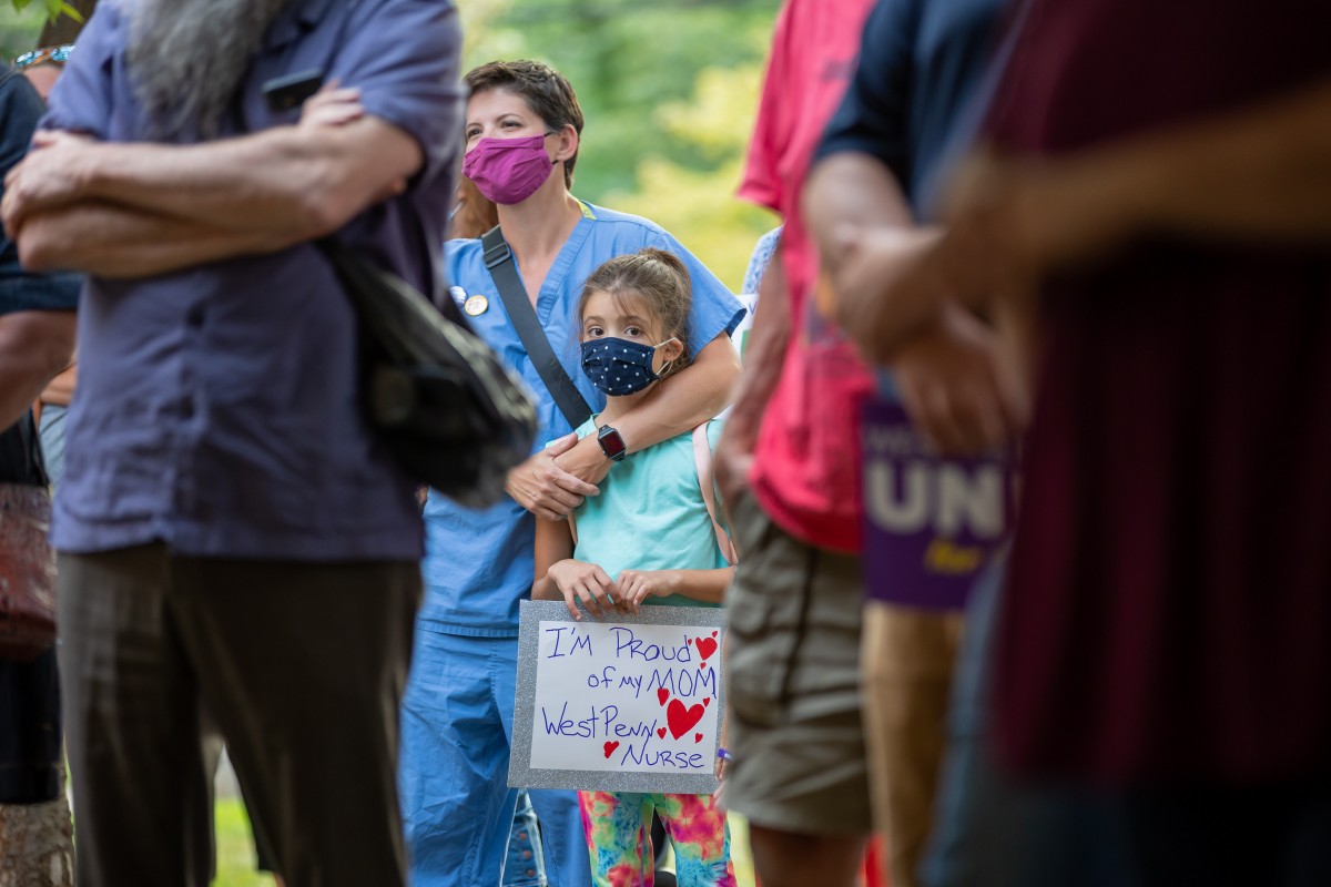 Dani Miller holds a sign during a rally to support unionization efforts outside West Penn hospital on August 3, 2021. Dani’s mother Sam, left, is a second-generation healthcare worker at West Penn. Photo: David Smith/100 Days in Appalachia